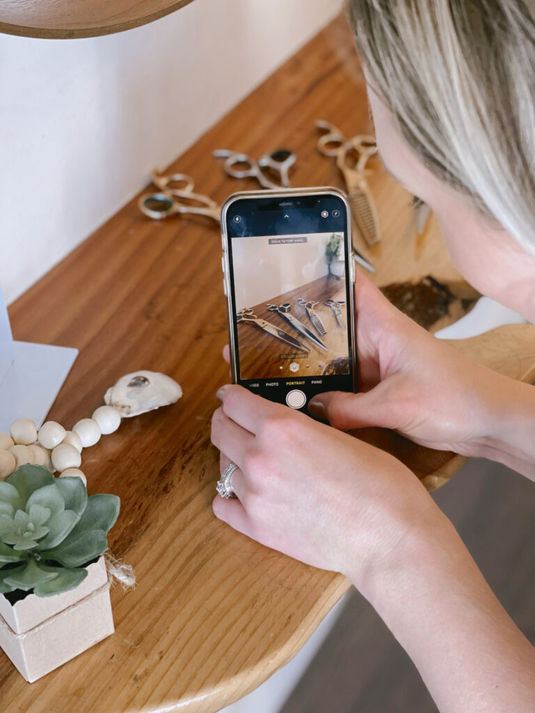 A person taking a closeup image on a phone camera of scissors artfully arranged.